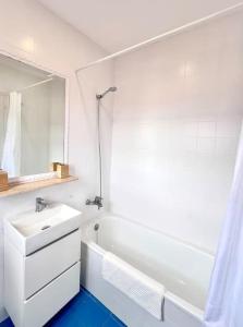 une salle de bain blanche avec un lavabo et une baignoire dans l'établissement Ático con vistas al mar Cala enPorter, à Cala'n Porter