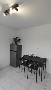 un tavolo nero con sedie e un frigorifero di Appartement cosy a Uchaud