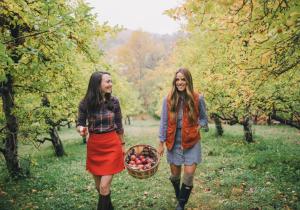 two women walking through an orchard with a basket of apples at 2 Lake Cabins Poolhottub Game Room & Courts in Highland Lake