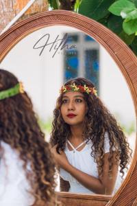 una joven está mirando su reflejo en un espejo en Hitha Maldives en Omadhoo