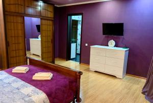 - une chambre avec des murs violets, un lit et une télévision dans l'établissement Brothers, à Tbilissi