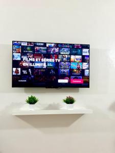 a flat screen tv hanging on a wall with two plants at Jolie Appt à skhirat 5min de la plage par voiture in Skhirat