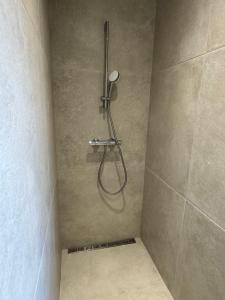 een douche met een slang in een douchecabine bij Chambre privée avec salle de bain partagée - La Brousse in Genay