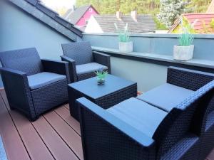 a patio with chairs and tables on a balcony at Ferienwohnung Am Waldesrand - Garten, Terrasse, Grill, Massagesessel, Kinderspielecke, Spielekonsole in Cottbus