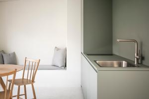 a kitchen with a sink and a table with a chair at Mynt Merano Rooms in Merano