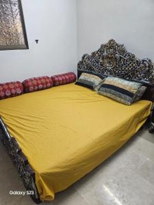 a yellow bed with pillows on top of it at Syed Rest House in Karachi