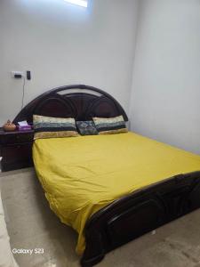 a bed with a yellow blanket and two pillows on it at Syed Rest House in Karachi