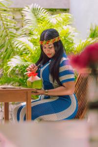 a woman sitting in a chair making a flower arrangement at Hitha Maldives in Omadhoo