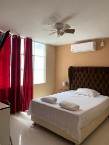 1 dormitorio con 1 cama grande y cortinas rojas en Hotel House Hoskins Talara- con AIRE ACONDICIONADO, uso de cocina, en Talara