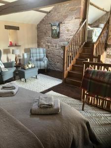 a living room with a bed and a staircase at Historic converted byre in courtyard of 16C house in Caldbeck