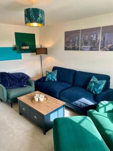 a living room with a blue couch and a table at 3-Bedroom Luxury Stay With FREE Parking in Market Harborough