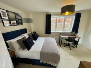 een slaapkamer met een bed, een bureau en een raam bij 3-Bedroom Luxury Stay With FREE Parking in Market Harborough