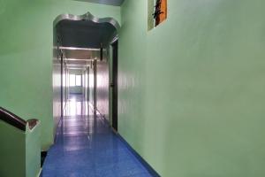 un pasillo con paredes verdes y un pasillo con puerta en OYO Savanna Garden Lodge en Pune