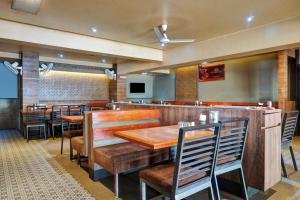 un restaurante con mesas y sillas de madera y un bar en OYO Savanna Garden Lodge en Pune