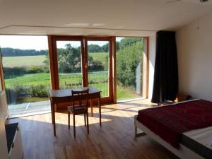 a bedroom with a desk and a bed and a large window at Toad 5 on the Soederbring in Waddeweitz