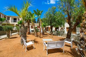a patio with two chairs and a table and palm trees at SanVitoTour- Residence Il Baglio in San Vito lo Capo