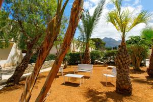 a resort yard with palm trees and chairs and tables at SanVitoTour- Residence Il Baglio in San Vito lo Capo