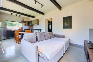 a living room with a white couch and a kitchen at Moderna do Prumirim in Ubatuba