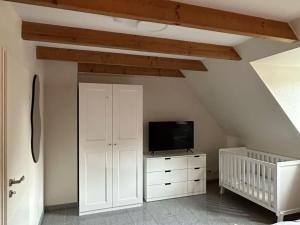 une chambre avec un berceau et une télévision sur une commode dans l'établissement Raceweide - MarBi Alles inbegrepen, à Dangast