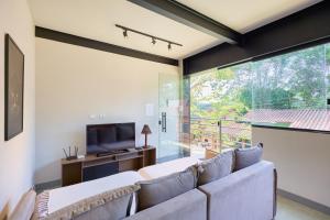 a living room with a couch and a television at Moderna do Prumirim in Ubatuba