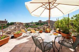 patio con tavolo, sedie e ombrellone di Hotel Minerva a Siena