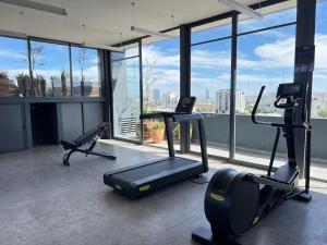 un gimnasio con equipo cardiovascular en una habitación con ventanas en Acogedor Departamento 2 Habitaciones, Alberca, Gym, en Guadalajara