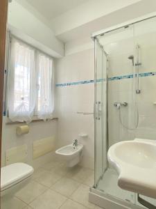 bagno bianco con lavandino e doccia di Appartamenti Vacanze Vista mare ad Alba Adriatica
