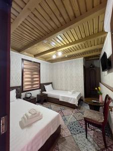 Un dormitorio con dos camas y una mesa y una silla. en Vaziri A'zam Hotel, en Bukhara
