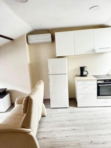 a kitchen with white cabinets and a couch in a room at Appartement entier full équipé in Charleroi