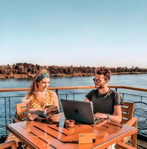 a man and woman sitting at a table with a laptop at NILE CRUISE LUXOR & ASWAN L in Aswan