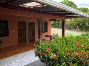eine Terrasse eines Hauses mit einem Tisch und Blumen in der Unterkunft Corcovado Hostel in Puerto Jiménez