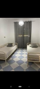 2 camas en una habitación con suelo a cuadros en Maison avec terrasse et spa, en Oujda