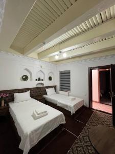una habitación con dos camas y una ventana en Vaziri A'zam Hotel, en Bukhara 46 fotos más