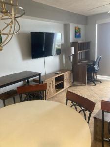 een woonkamer met een televisie en een tafel en stoelen bij Ocean Walk Resort 1305 in Daytona Beach