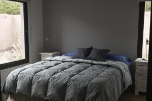 a bedroom with a bed with blue sheets and a window at Moller Masi - Ayllu Huasi in Purmamarca +3 photos