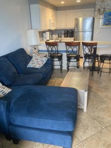 een woonkamer met een blauwe bank en een keuken bij Ocean Walk Resort 1305 in Daytona Beach