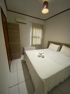 een slaapkamer met een wit bed met twee schoenen erop bij House Anthony and Cleusa 36 Quinta do Rio in Pipa