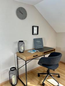 una scrivania con sedia e un orologio appeso a un muro di Danny's Wörtherseeblick a Schiefling am Wörthersee
