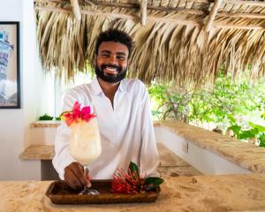 een man die aan een balie staat met een drankje bij Boutique Hotel Las Flores Punta Cana in Punta Cana