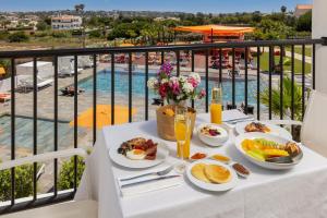 uma mesa com comida para o pequeno almoço numa varanda com piscina em Regency Salgados Hotel & Spa em Albufeira