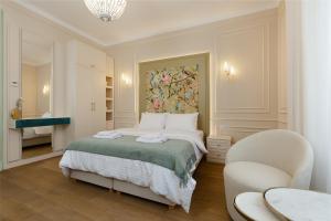 a white bedroom with a bed and a chair at 1910 Boutique Hotel in Braşov