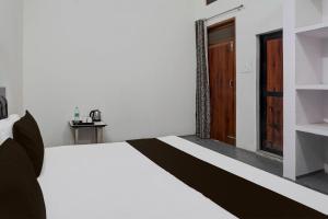 - une chambre avec un lit blanc et une porte en bois dans l'établissement OYO Atithi Guest House, à Kāshīpur