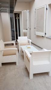 a group of white chairs and tables in a room at LOFT CON CORTILE in Forlì