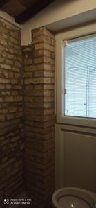 a bathroom with a brick wall and a window at LOFT CON CORTILE in Forlì