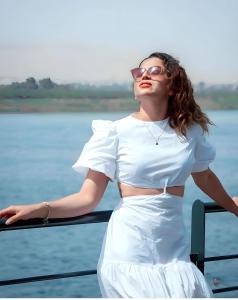 a woman in a white dress standing next to a body of water at NILE CRUISE LUXOR & ASwAN نايل كروز الاقصر و اسوان in Luxor