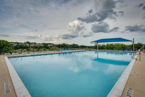 a large swimming pool with chairs and a blue umbrella at Lago Vista Golf Getaway with Decks and Pool Access! in Lago Vista
