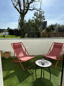 twee roze stoelen en een tafel op een gazon bij Arradon Golfe du Morbihan Appartement 2 Pièces plain-pied Terrasse in Arradon