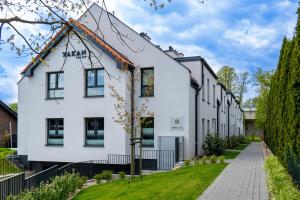 a white building with black windows on a street at Stary Tartak nad jeziorem Drwęckim - MAZURIA APARTAMENTY in Ostróda