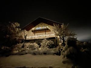 un edificio cubierto de nieve con luces. en Bergchalet Mirabell - Hofgut, en Friedrichshafen