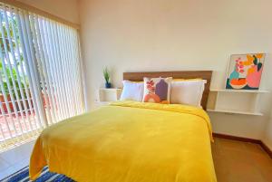 a bedroom with a yellow bed and a window at Palma Sol in Pampatar